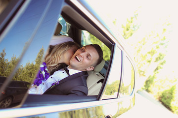 Bride and groom having fun in the car