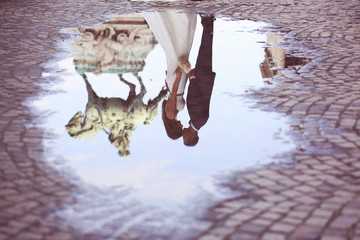 Bride and groom reflected in slop on paved road
