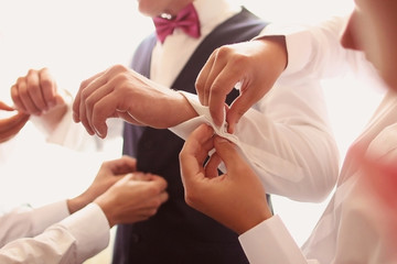 Hands helping the groom with buttons