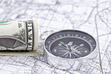 Fototapeta na wymiar twisted one-dollar bill and a compass lying on a map