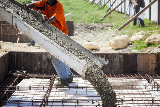 Trabajador vertiendo concreto desde una mezcladora para fundir la placa de los cimientos de una construcci&oacute;n