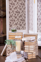 Old books heap and candle in vintage interior decoration