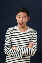 Laughing young Asian man with crossed hands looking at camera