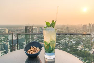 Fotobehang Mojito cocktail and cashews on table in rooftop bar © ake1150