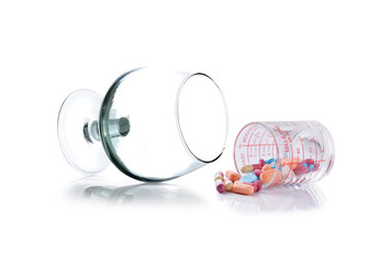 glass and Heap of medicine pills.