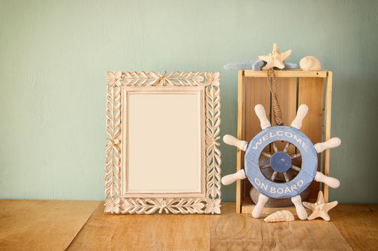 old vintage frame with naurical wheel on wooden table. vintage f