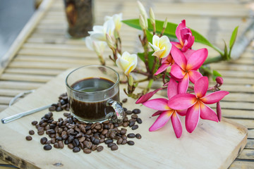 Cup of coffee with coffee beans on a beautiful flower.