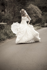 Fototapeta na wymiar Pretty young bride walking down road in wedding gown