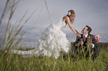 Happy newly wed couple outdoors in field of long grass