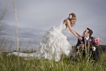 Happy newly wed couple outdoors in field of long grass