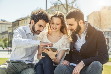 Three young friends at the park using a tablet