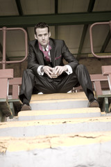 Handsome young man in suit sitting on yellow strip staircase