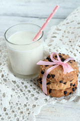 Tasty cookies and glass of milk on color wooden background