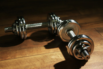 Dumbbells on wooden floor, on dark background