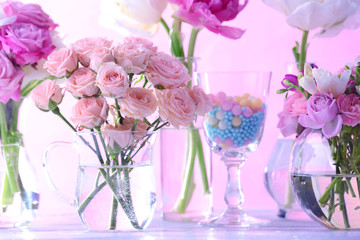 Beautiful spring flowers in glass vases on light pink