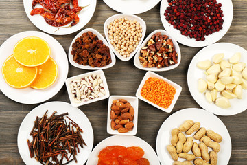 Different products on saucers on wooden table, top view