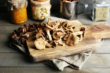 Dried mushrooms on cutting board on wooden background