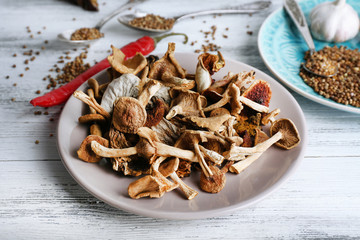 Dried mushrooms in plate on wooden background