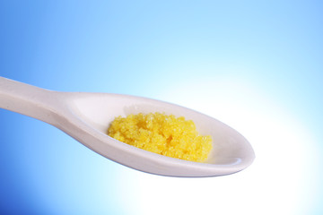 Laboratory spatula with granules on blue background