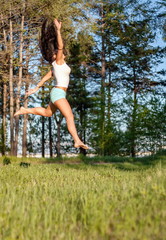 Obraz na płótnie Canvas Pretty woman jumping on green field.