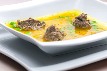 homemade liver dumplings in chicken soup with carrots and peas