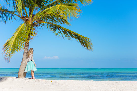 Woman standing under palm tree on tropical beach