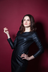 Portrait of young beautiful woman in leather dress on red