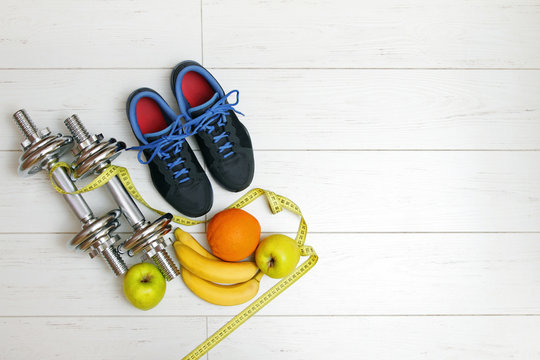 fitness equipment and fruits on white wooden plank floor