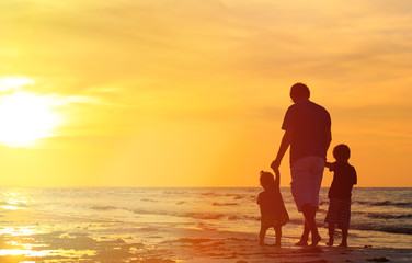 father and two kids walking at sunset