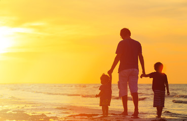 father and two kids walking at sunset