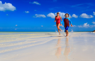 mother and son running in water on the beach