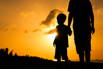 Fototapeta na wymiar father and son holding hands at sunset sea