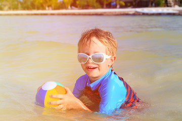 little boy playing ball on summer beach