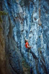 Rock climber climbing up a cliff