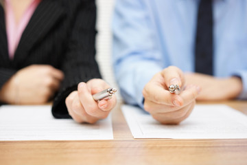 Two agents giving his client a pen to sign a deal