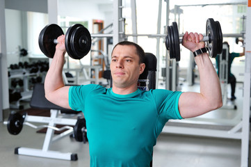 Fototapeta na wymiar Man lifting dumbbells in a fitness club