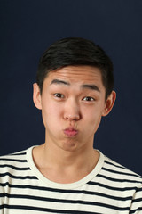 Funny young Asian man making face and looking at camera