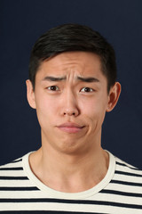Disgusted young Asian man looking at camera