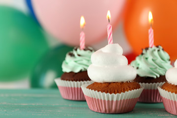 Delicious birthday cupcakes on table on bright background