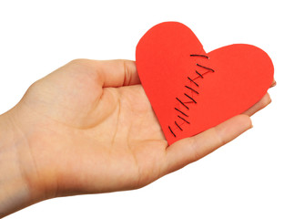 Female hand holding broken heart stitched from two pieces isolated on white