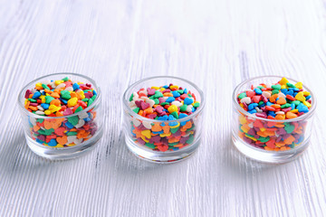Colorful sprinkles in bowls on table close-up