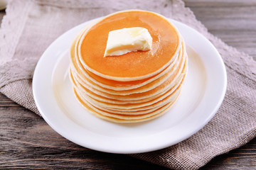 Delicious pancakes with honey on plate on table close-up