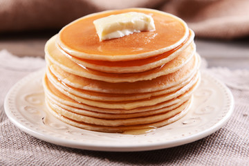 Delicious pancakes with honey on plate on table close-up
