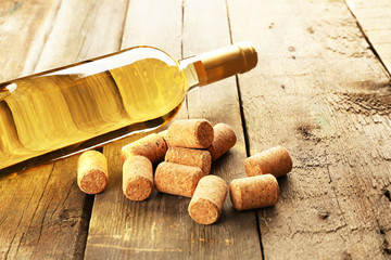 Glass bottle of wine with corks on wooden table background