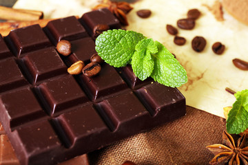 Chocolate with mint, spices and coffee beans on table, closeup