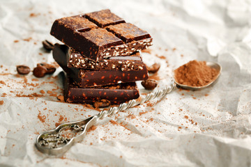 Pieces of chocolate with cocoa on parchment, closeup