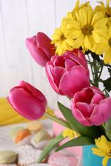 Composition of spring flowers, tea and cookies on table