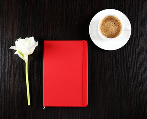 Cup of coffee with notebook and fresh flower