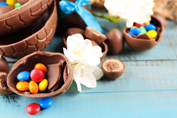 Chocolate Easter eggs with flowers on wooden table, closeup