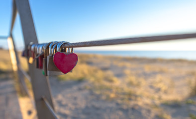 Padlocks with red heart shape on Dutch beach